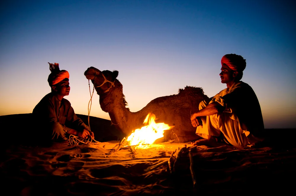 indian-men-resting-by-bonfire-with-their-camel